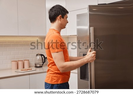 Man opens refridgerator, dealing with hunger in a home kitchen