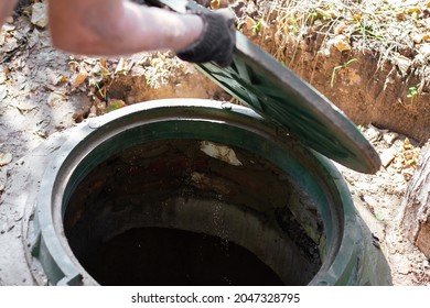 The Man Opens A Sewer Hatch. Septic Tank Inspection And Maintenance.