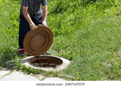 A man opens a sewer hatch. Sewage repair. Theft of iron manholes for sewerage with further sale for scrap metal. - Powered by Shutterstock