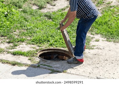 A man opens a sewer hatch. Sewage repair. Theft of iron manholes for sewerage with further sale for scrap metal.	 - Powered by Shutterstock