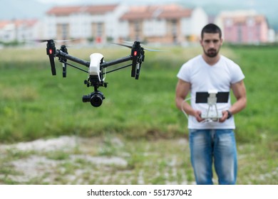 Man Operating Drone Flying or Hovering by Remote Control in Nature
