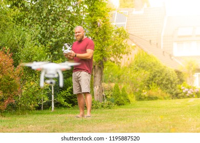 Man operating a drone with remote control - happy guy playing with a quadricopter in the garden (outdoor) on a sunny day - flying quadcopter image with copy space