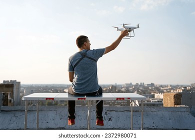 Man operating a drone with remote control on rooftop