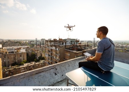 Man operating a drone with remote control on rooftop