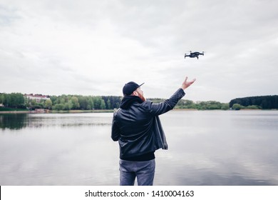 Man operating / flying with drone by the river. Back view shot 