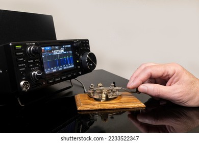 Man operating morse code key with a modern radio transceiver.