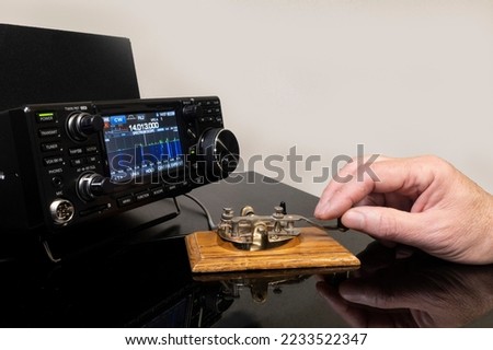 Man operating morse code key with a modern radio transceiver.
