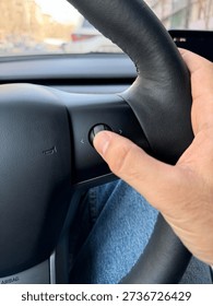 Man Operating Multi-Functional Scroll Button on Modern EV Steering Wheel - Minimalist Interior and Intuitive Car Control Technology