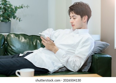 A man operating a smartphone while relaxing on the sofa