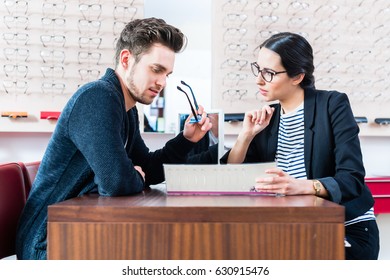 Man At Optician Shop Getting Advice From Sales Woman