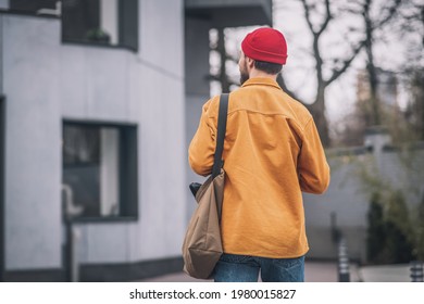 Man in an orange jacket walking down the street