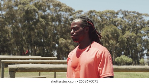 Man in orange shirt focusing during outdoor bootcamp training in forest setting. Exercise, fitness, outdoors, nature, workout, athletics - Powered by Shutterstock