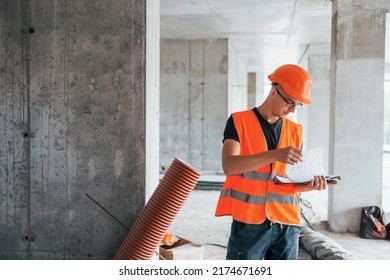 Man in orange uniform and hard hat is working on the construction. - Shutterstock ID 2174671691