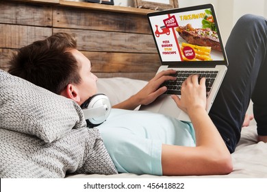 Man Ordering Take Away Food By Internet With A Laptop While Lying At Home.
