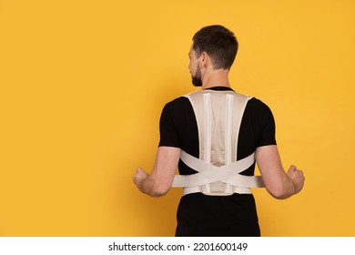 Man With Orthopedic Corset On Orange Background, Back View. Space For Text