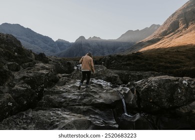 Man in outdoor attire hikes through rocky terrain in a mountain landscape. Man walking in the rocky path in mountain. The rocky terrain and nature mountain landscape with a man walking. Mountain - Powered by Shutterstock