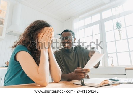 A man is outraged by an expensive check after his wife's purchases. A woman covers her face in dismay while a man looks on with an expression of concern, both reacting to a document in a bright
