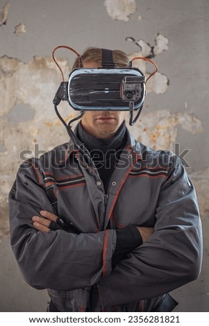A man in overalls with a cyber helmet on his head, a portrait against a shabby wall, high technology and a low standard of living of society, concept
