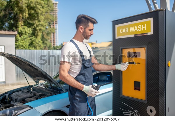 Man in overalls near\
machine at car wash