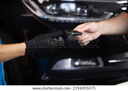 Man owner of the auto gives the keys to the car repairman. Vehicle breaks down. Close up shot of hands of male client giving car key to mechanic in auto repair shop. Car repair.