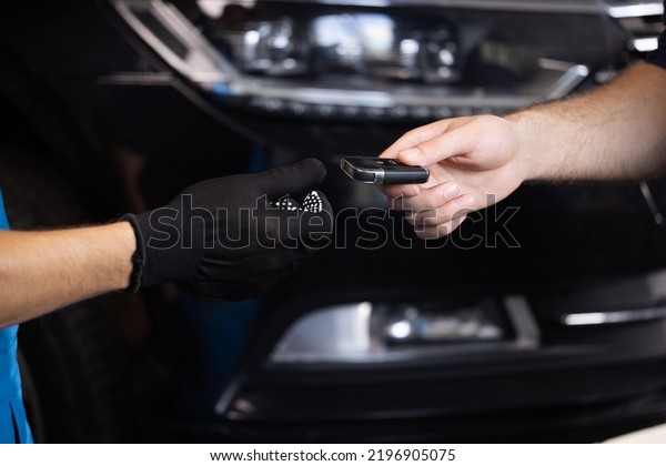 Man owner of\
the auto gives the keys to the car repairman. Vehicle breaks down.\
Close up shot of hands of male client giving car key to mechanic in\
auto repair shop. Car\
repair.