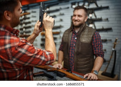 Man with owner choosing handgun in gun shop