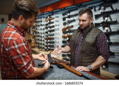 Man With Owner Choosing Handgun In Gun Shop