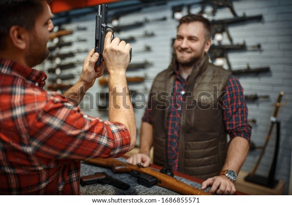 Man with owner\
choosing handgun in gun\
shop