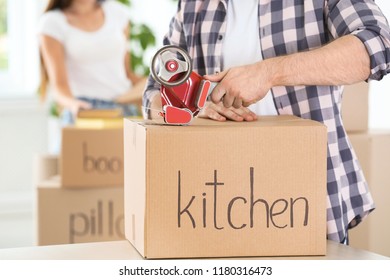 Man packing cardboard box indoors, closeup. Moving day - Shutterstock ID 1180316473