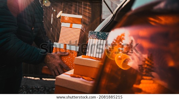 man packing Christmas\
gift boxes in car