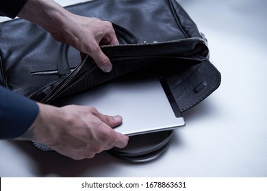 Man Is Packing His Laptop In Black Leather Bag. Person Is Getting Tablet From Men's Briefcase For Travel Office Business. Useful Bag For Trip. Spacious Traveling Bag