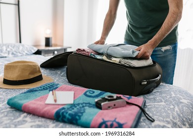 Man packing his suitcase in the bedroom at home. Travel vacation and holidays concept - Powered by Shutterstock