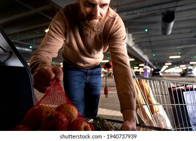 Man Packing Shopping Bags In A Car Trunk                               