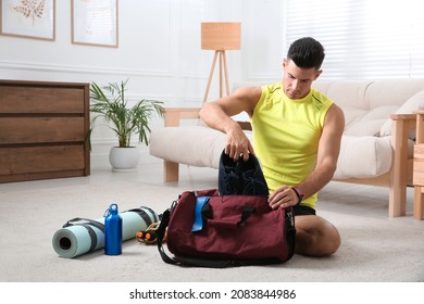 Man packing sports stuff for training into bag at home