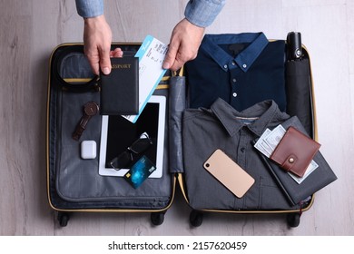 Man Packing Suitcase For Business Trip On Wooden Floor, Top View