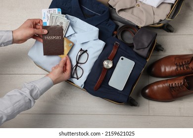 Man Packing Suitcase For Business Trip On Wooden Floor, Top View