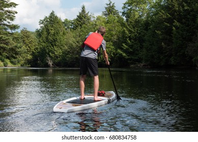 Man Paddle Boarding During Summer, Muskoka, Ontario, Canada. 