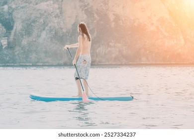 Man Paddleboarding Lake Sunset: Man enjoys a relaxing paddleboard session on a calm lake at sunset, surrounded by majestic mountain scenery. - Powered by Shutterstock