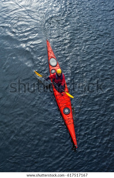 man paddles a white kayak on the river near\
the shore, kayaking view from\
above