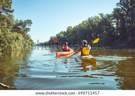 Man paddling in a kayak on river.