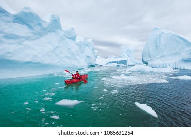 man paddling on kayak between ice in Antractica in Iceberg Graveyard, extreme winter kayaking, polar adventure near Pleneau island