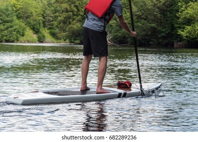 Man Paddling On A Stand Up Paddle Board, Muskoka, Ontario, Canada.