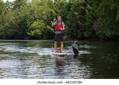 Man Paddling On A Stand Up Paddle Board, Muskoka, Ontario, Canada.