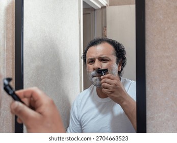man with a pained expression while shaving his face