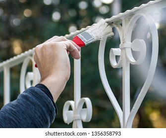 Man painting with brush outdoor fence in white, close up