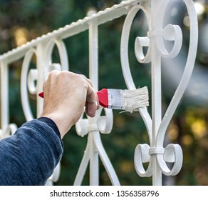 Man painting with brush outdoor fence in white, close up