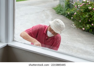 Man Painting And Cleaning Window Frame Outside Of The House. Home Refurbishment Do It Yourself Project. 