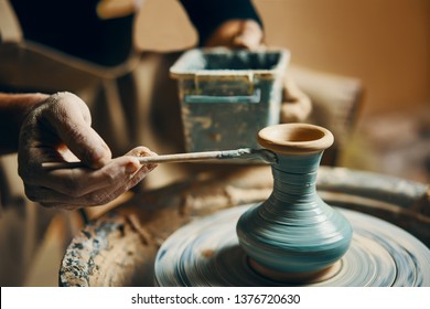 Man painting handmade pottery at ceramic workshop. Art concept - Powered by Shutterstock