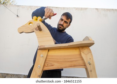 Man Painting Homemade Giraffe-shaped Rocking Horse