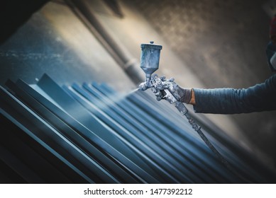Man painting metal products with a spray gun